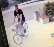 Zdjęcie z monitoringu, na nim poszukiwany mężczyzna jadący na rowerze