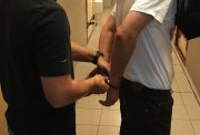 Policjant zakłada kajdanki osobie zatrzymanej