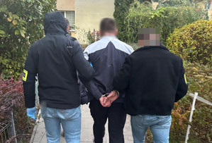 zatrzymany mężczyzna w asyście umundurowanych policjantów