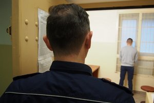 Policjant z mężczyzną w pomieszczeniu dla osób zatrzymanych