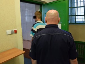 Policjant z zatrzymanym mężczyzną w pomieszczeniu dla osób zatrzymanych