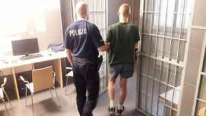 Policjant prowadzi zatrzymanego mężczyznę