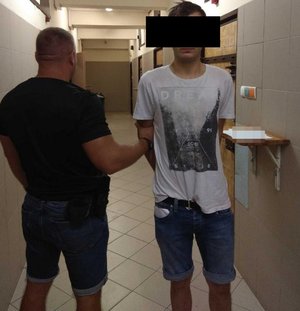 Policjant wykonuje czynności z zatrzymanym mężczyzną