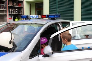 na zdjęciu widać policyjny radiowóz i dzieci siedzące w środku