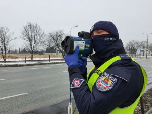 Zdjęcie przedstawia policjanta ruchu drogowego dokonującego pomiaru prędkości.