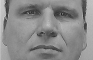 Zdjęcie jest szare, przedstawia fragment twarzy mężczyzny patrzącego na wprost obiektywu aparatu.