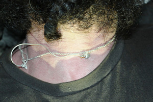 Zdjęcie przedstawia fragment sylwetki osoby, od brody do klatki piersiowej. Na szyi widać dwa łańcuszki koloru białego z zawieszką w kształcie serca.