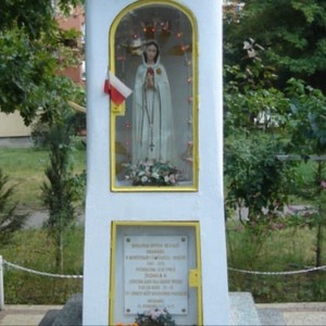 Zdjęcie przedstawia figurkę Matki Boskiej umieszczonej w kapliczce.