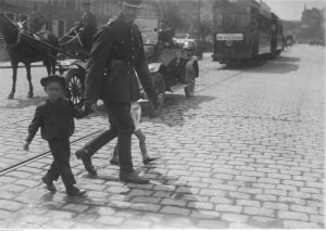 Policjant przeprowadzający dzieci przez ulicę. Rok 1925. Żródło: Narodowe Archiwum Cyfrowe