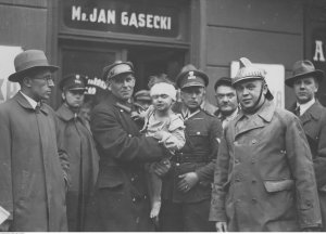Policjanci z uratowanym spod gruzów dzieckiem na ulicy Freta. Warszawa 1935. Źródło: Narodowe Archiwum Cyfrowe